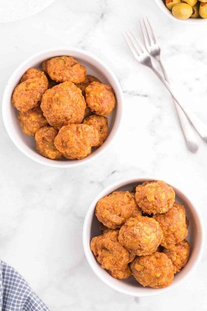 Golden baked olive cheese balls with a savoury cheese coating and olives tucked inside, served as bite-sized appetizers.