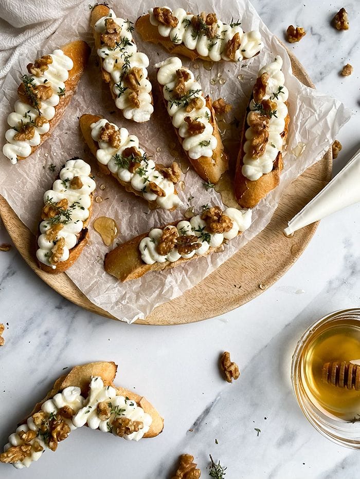 Toasted baguette slices topped with creamy ricotta cheese, honey, chopped walnuts, and fresh thyme.