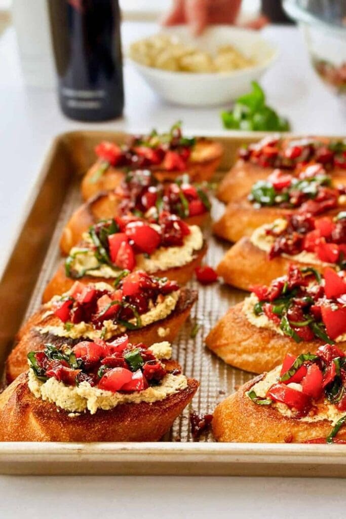 Toasted baguette slices topped with a flavourful sun-dried tomato bruschetta mixture, fresh herbs, and olive oil.