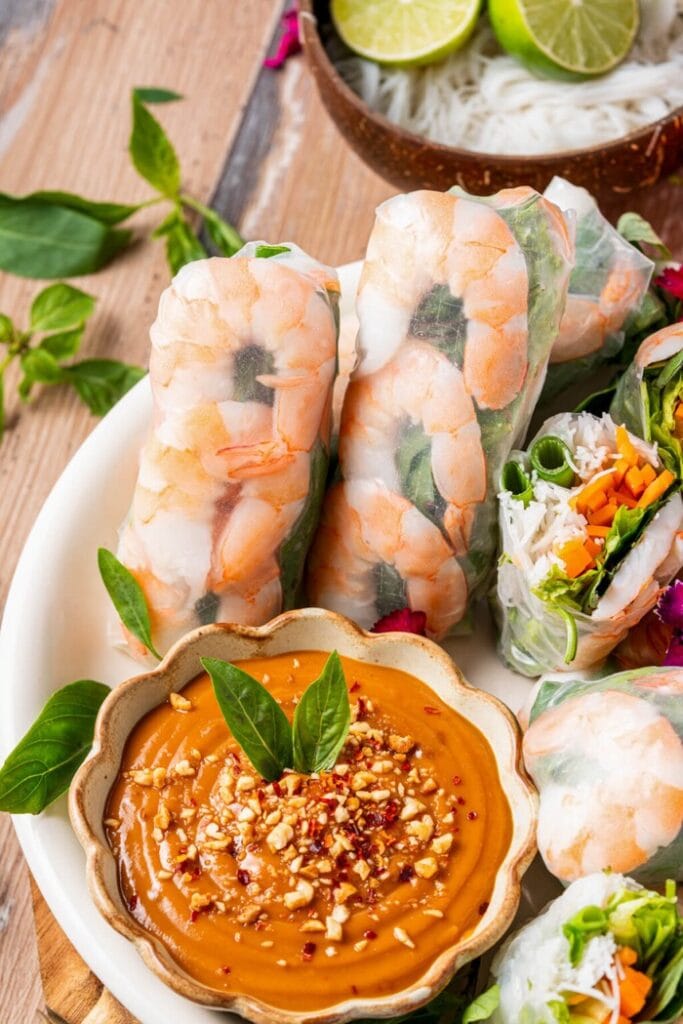 Fresh Vietnamese shrimp salad rolls wrapped in rice paper with rice noodles, colourful vegetables, and herbs, served with peanut dipping sauce.